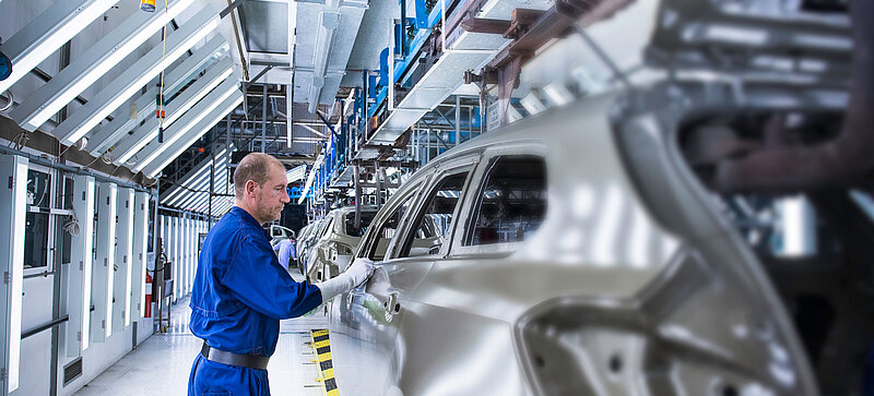 
		  A man working on a car at a manufacturing plant