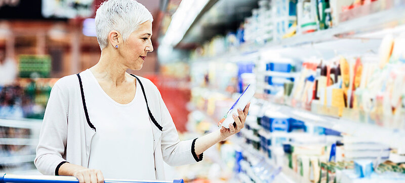 
		  A woman standing in front of the chilled goods section in the supermarket